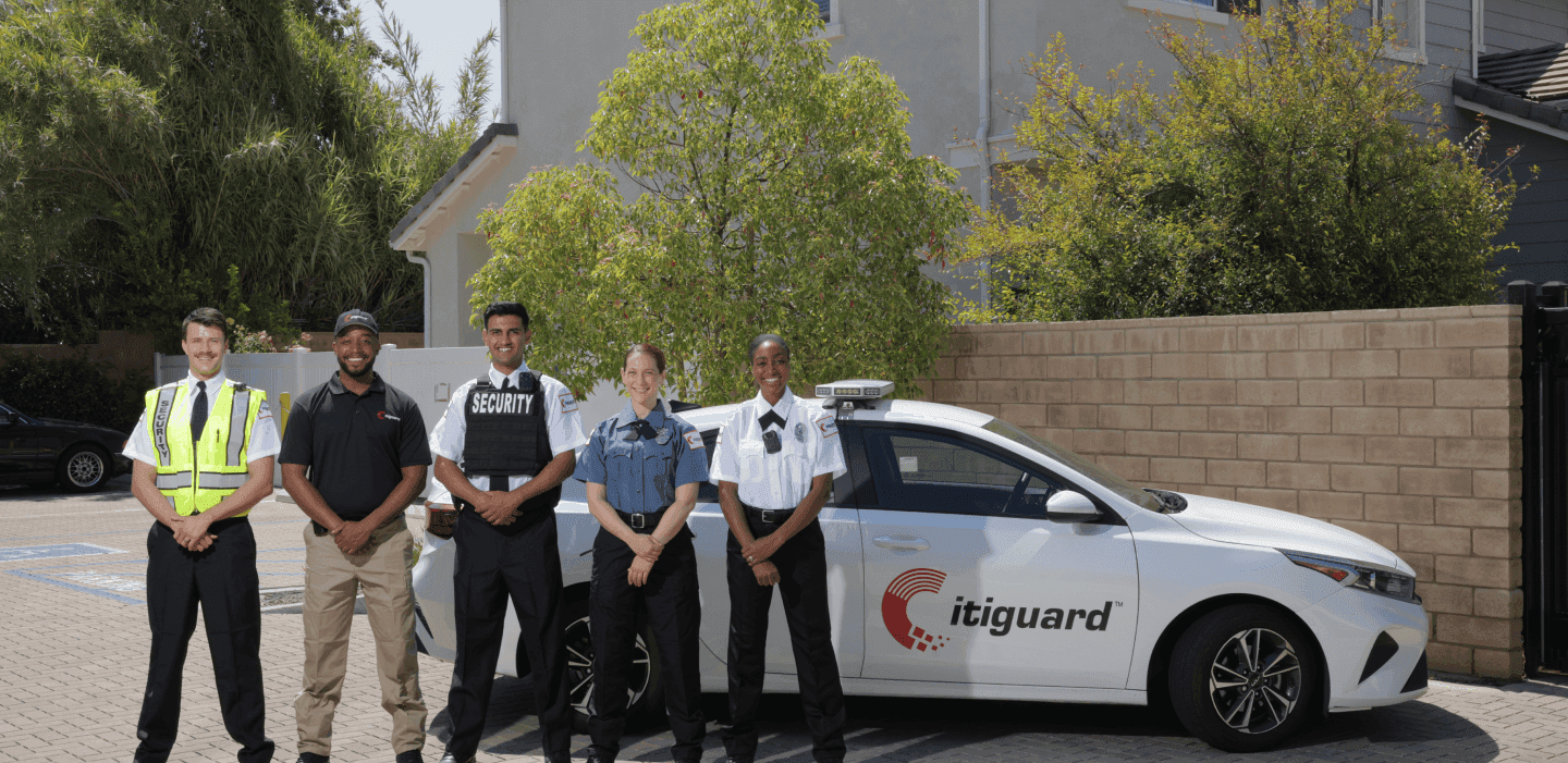 Citiguard patrol officers standing beside a marked Citiguard patrol car outside a residential community
