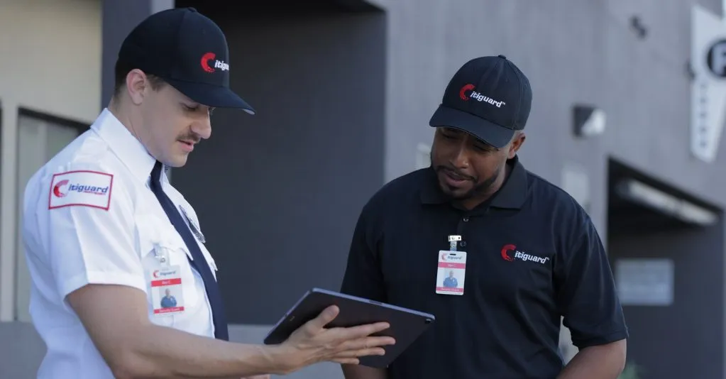 (Two Citiguard security officers review information on a tablet outside a building, showcasing professional collaboration and the use of modern technology in private security operations.)