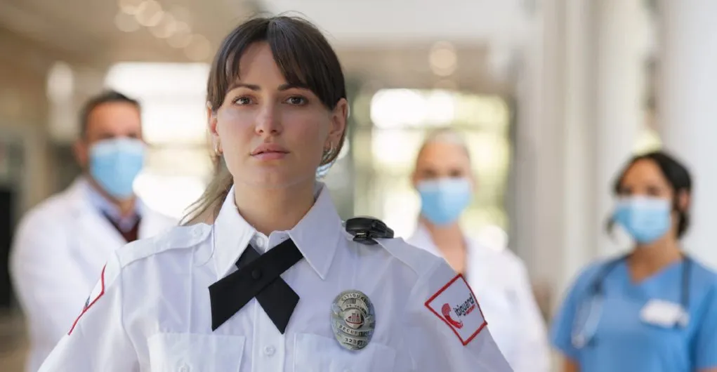 (A determined hospital security officer stands at the forefront with medical staff in the background, symbolizing teamwork and commitment to safety in healthcare environments.)