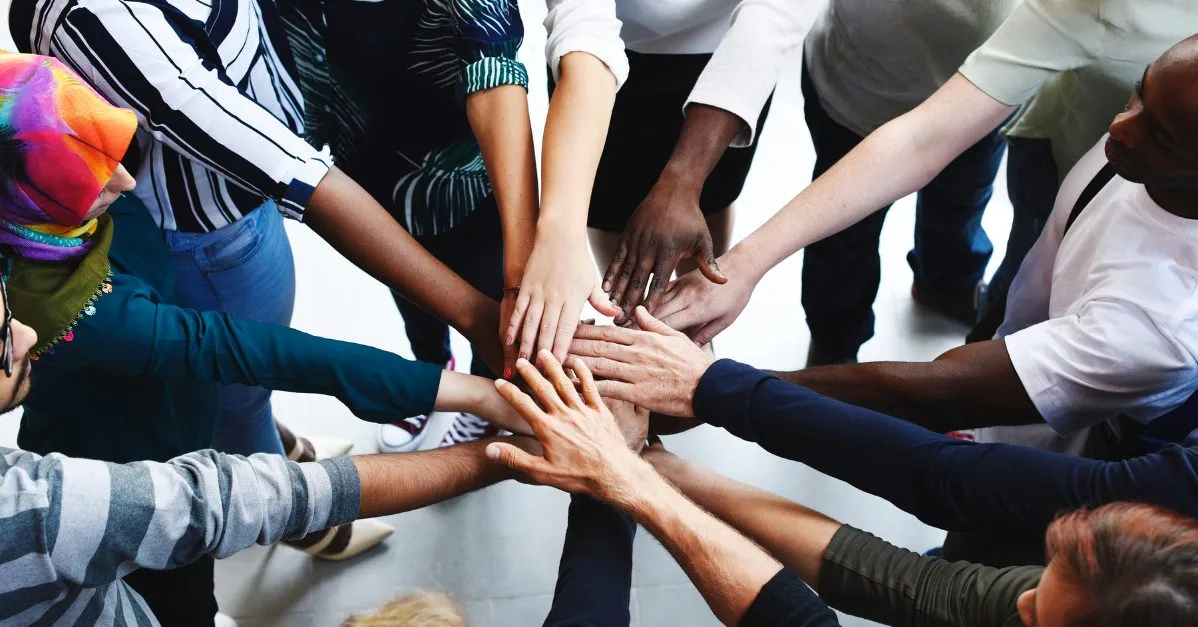 (many people’s hands in a break huddle)